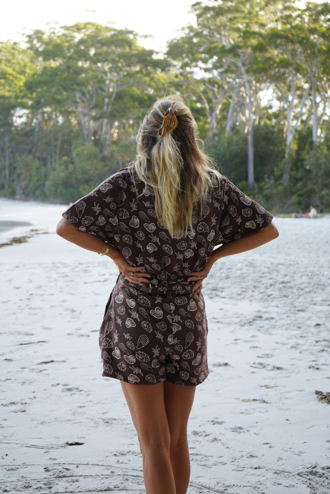 Woman wearing brown patterned towel-wear. This wearable towel is made from Organic Cotton and a towel outfit.