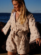 Woman wearing brown patterned towel-wear. This wearable towel is made from Organic Cotton and a towel outfit.