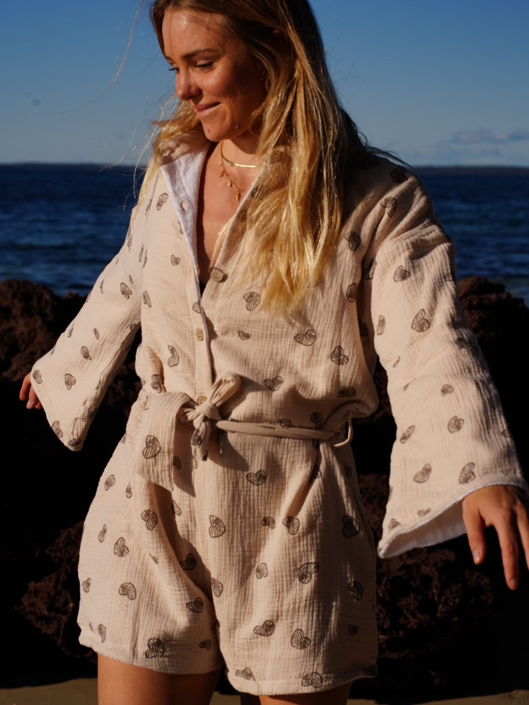 Woman wearing brown patterned towel-wear. This wearable towel is made from Organic Cotton and a towel outfit.
